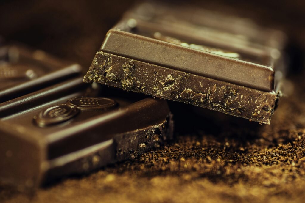 chocolate-dark-coffee-confiserie-65882-65882 Macro shot of rich dark chocolate bars sprinkled with cocoa powder, highlighting texture and indulgence.